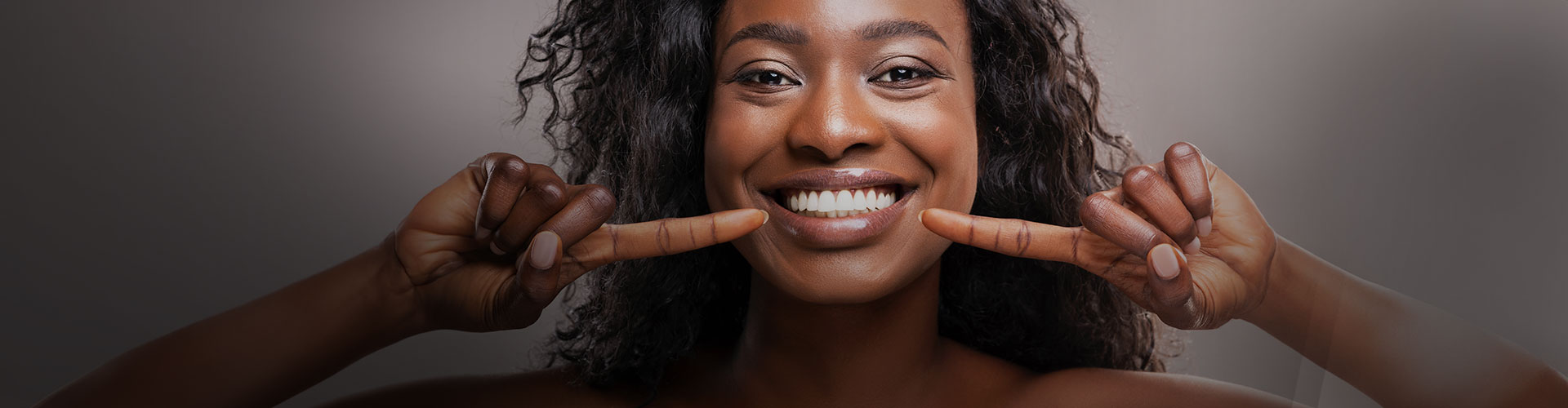 mulher negra apontando para os próprios dentes saudáveis